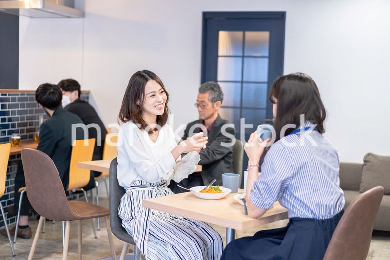 明るい雰囲気の社員食堂でランチを取るオフィスワーカー