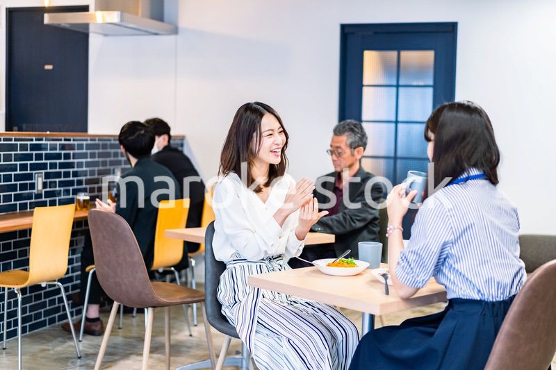 明るい雰囲気の社員食堂でランチを取るオフィスワーカー