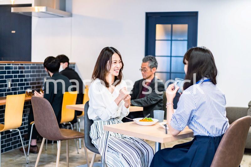 明るい雰囲気の社員食堂でランチを取るオフィスワーカー