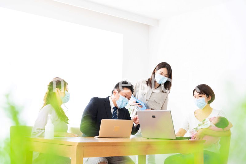 赤ちゃんを連れてオフィスで働く女性