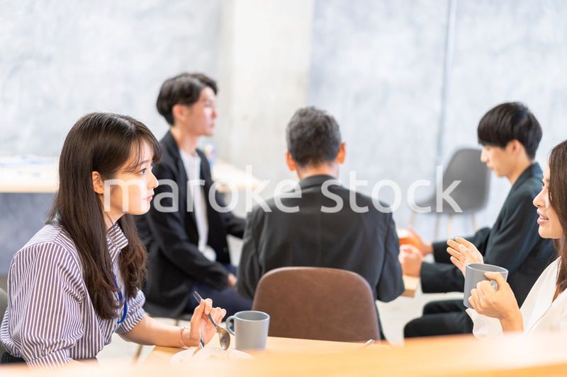 明るい雰囲気の社員食堂でランチを取るオフィスワーカー