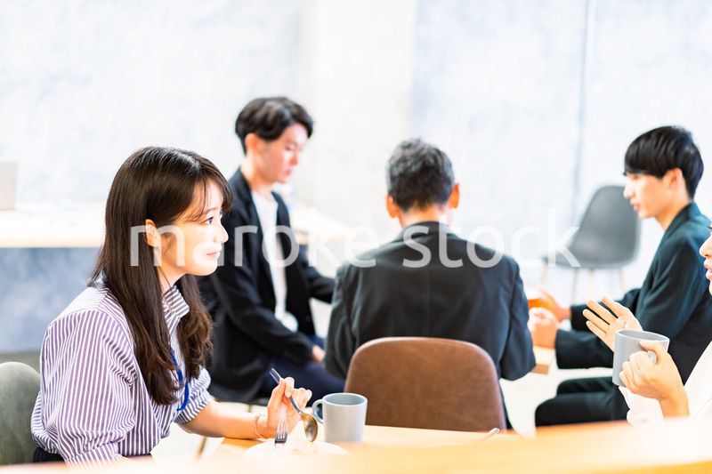 明るい雰囲気の社員食堂でランチを取るオフィスワーカー