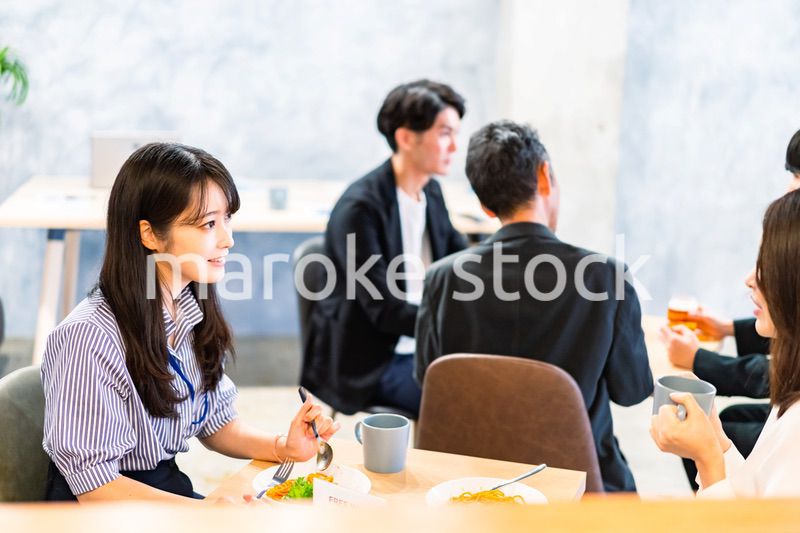 明るい雰囲気の社員食堂でランチを取るオフィスワーカー