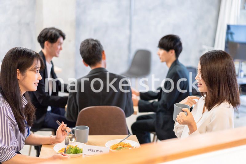 明るい雰囲気の社員食堂でランチを取るオフィスワーカー