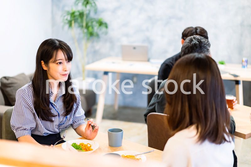 明るい雰囲気の社員食堂でランチを取るオフィスワーカー