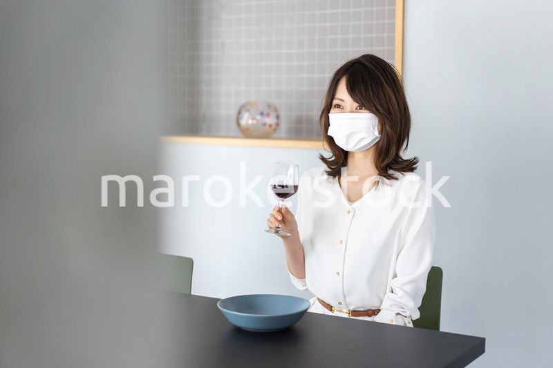 マスクをしてワインを飲む若い女性