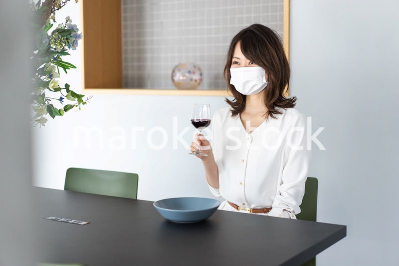 マスクをしてワインを飲む若い女性