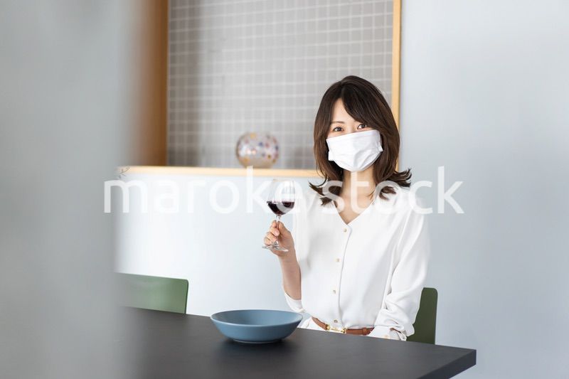 マスクをしてワインを飲む若い女性