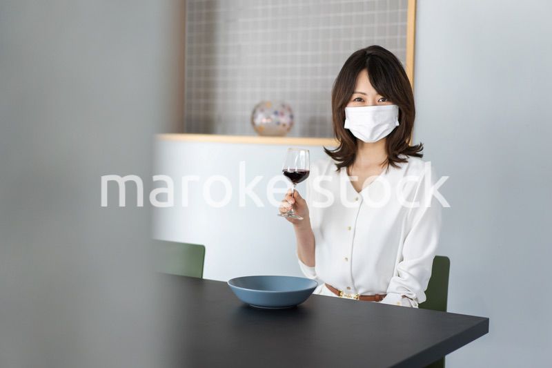 マスクをしてワインを飲む若い女性