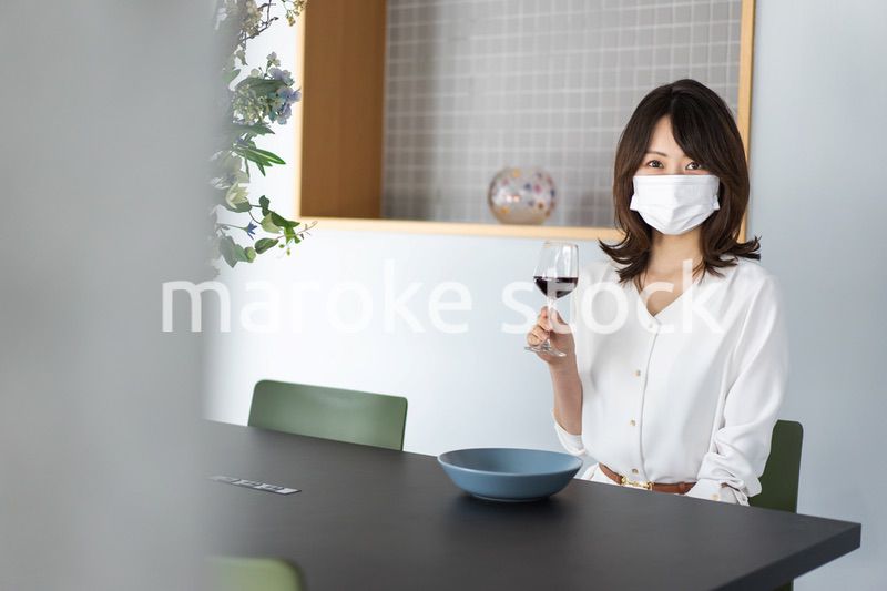 マスクをしてワインを飲む若い女性
