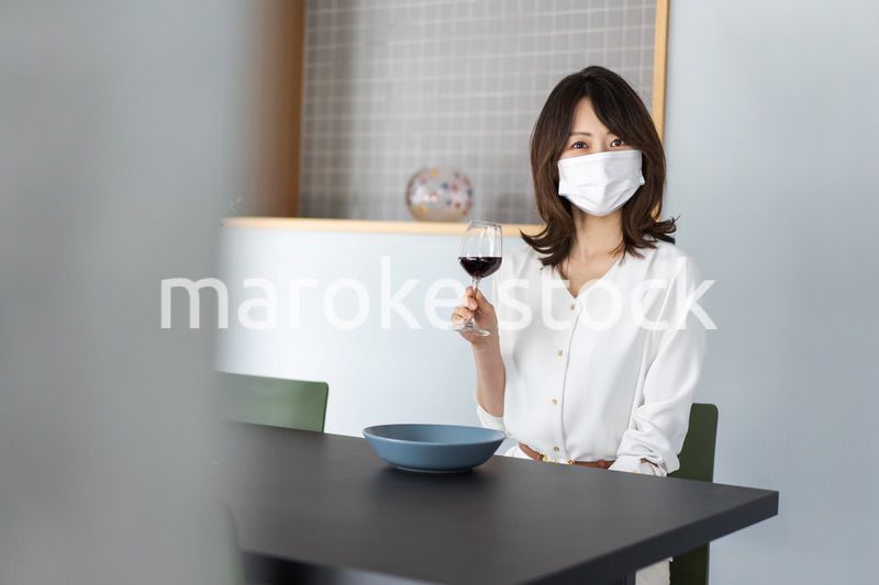 マスクをしてワインを飲む若い女性