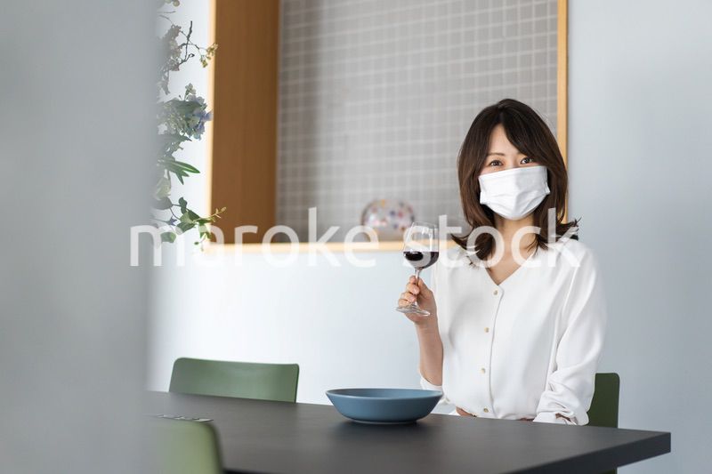 マスクをしてワインを飲む若い女性