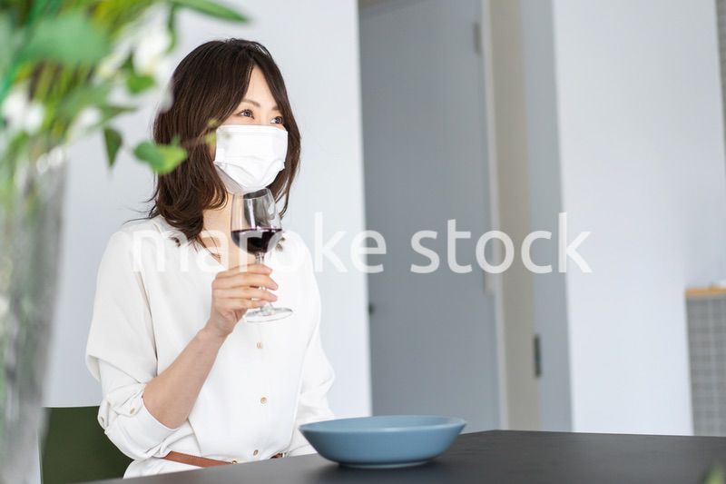 マスクをしてワインを飲む若い女性
