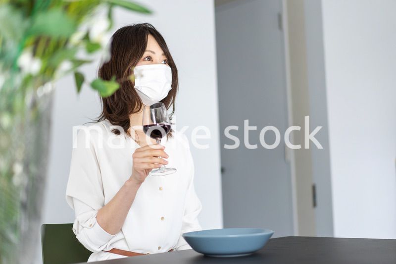 マスクをしてワインを飲む若い女性