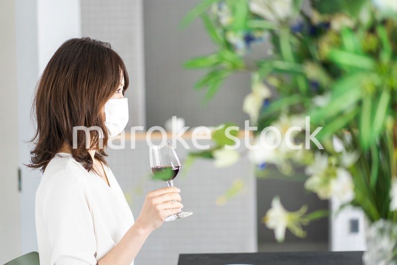 マスクをしてワインを飲む若い女性