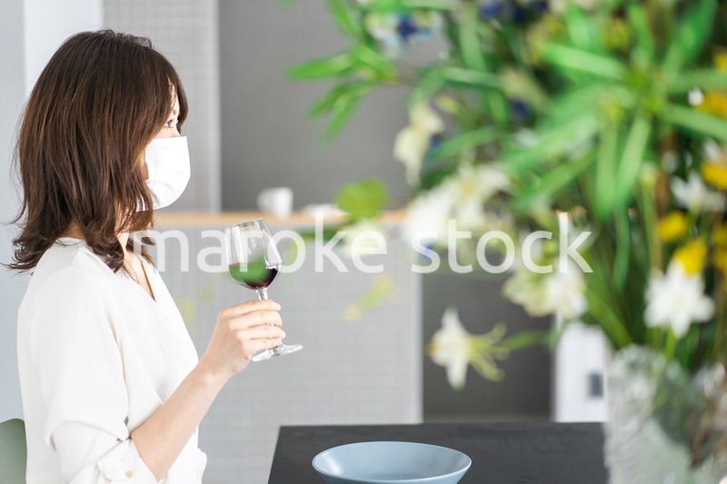 マスクをしてワインを飲む若い女性