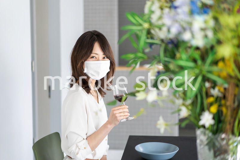 マスクをしてワインを飲む若い女性