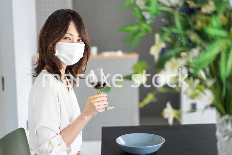 マスクをしてワインを飲む若い女性