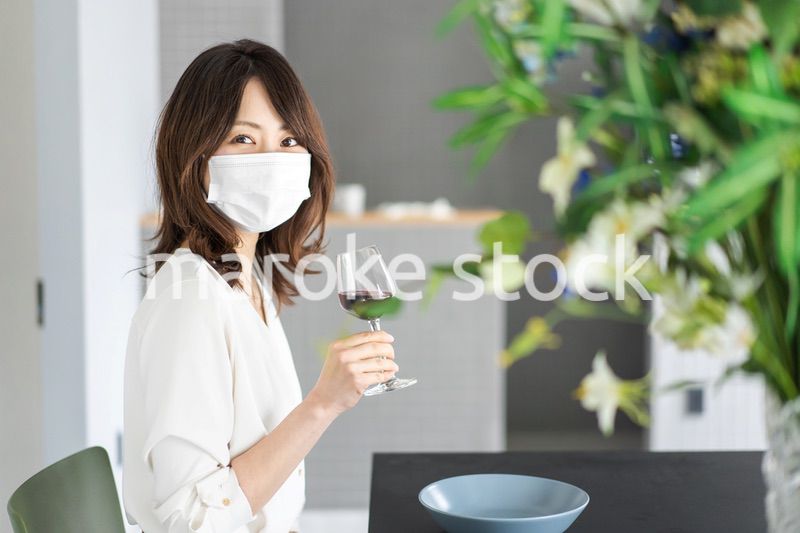マスクをしてワインを飲む若い女性