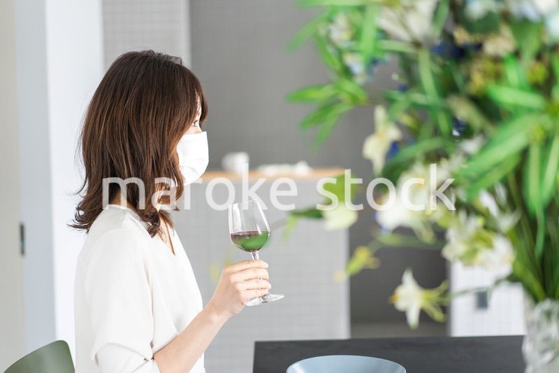 マスクをしてワインを飲む若い女性