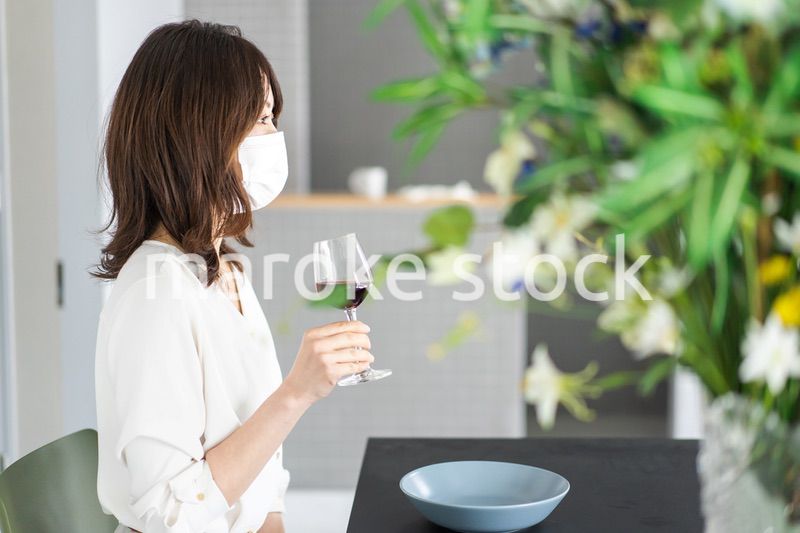 マスクをしてワインを飲む若い女性