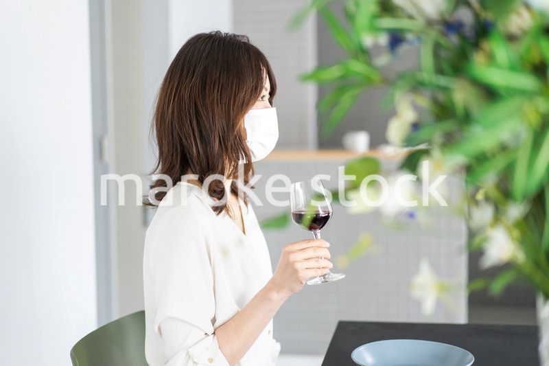 マスクをしてワインを飲む若い女性