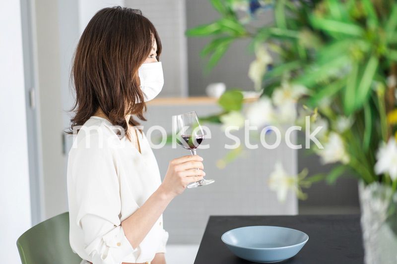 マスクをしてワインを飲む若い女性