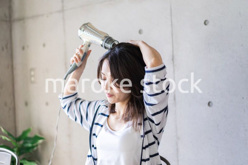 ドライヤーで髪を乾かす若い女性