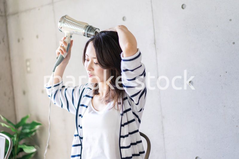 ドライヤーで髪を乾かす若い女性