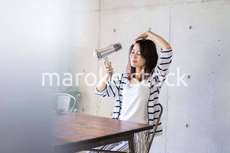 ドライヤーで髪を乾かす若い女性