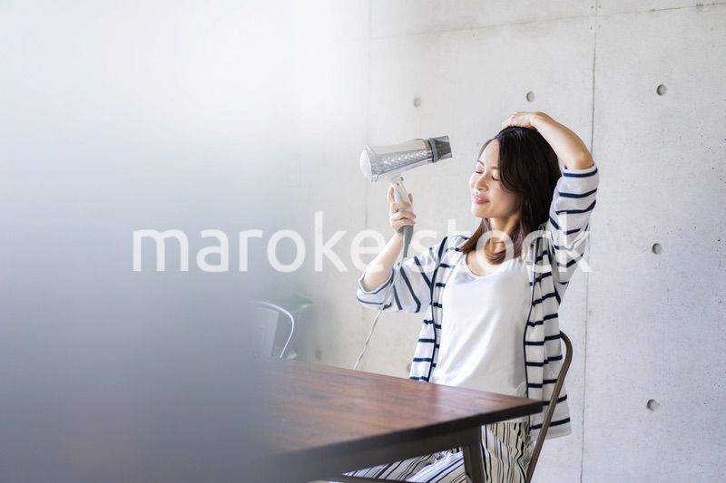 ドライヤーで髪を乾かす若い女性
