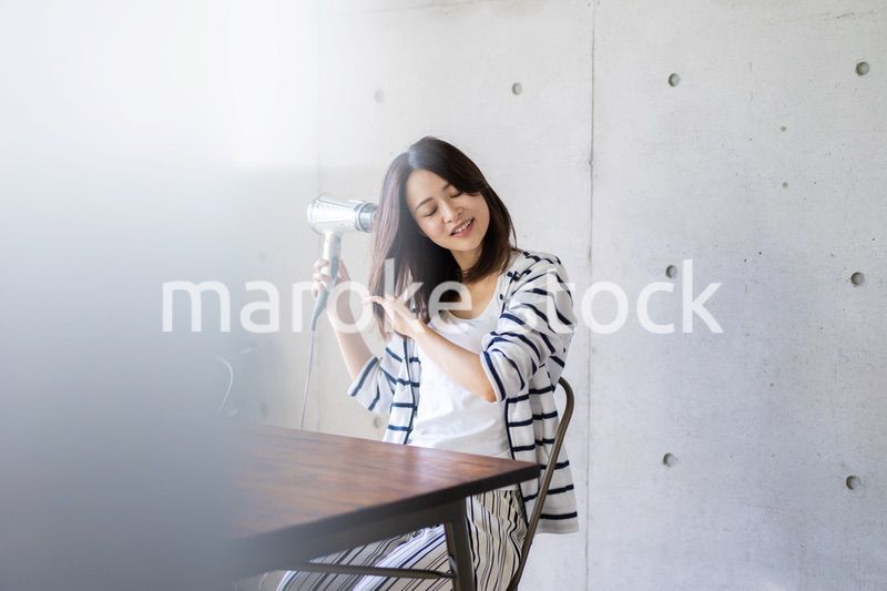 ドライヤーで髪を乾かす若い女性