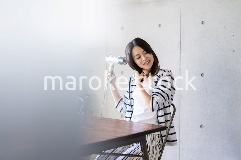 ドライヤーで髪を乾かす若い女性