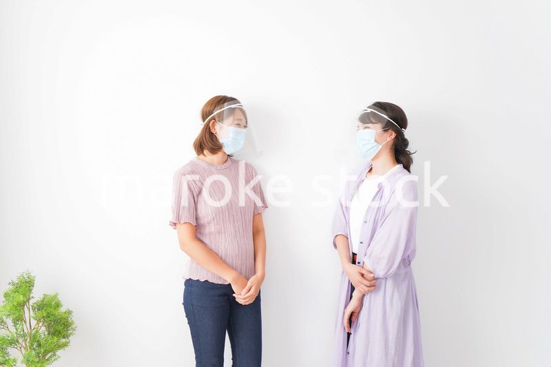 フェイスシールドをして話す若い女性