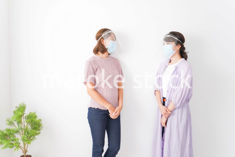 フェイスシールドをして話す若い女性
