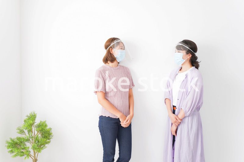フェイスシールドをして話す若い女性