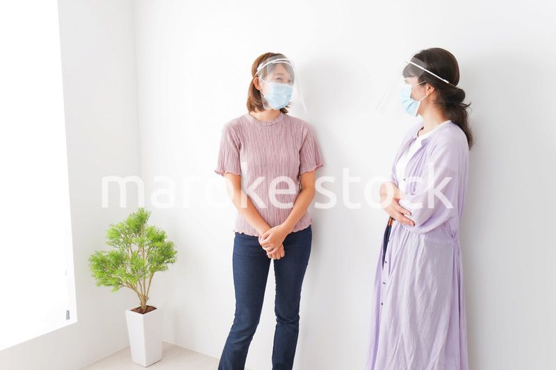 フェイスシールドをして話す若い女性
