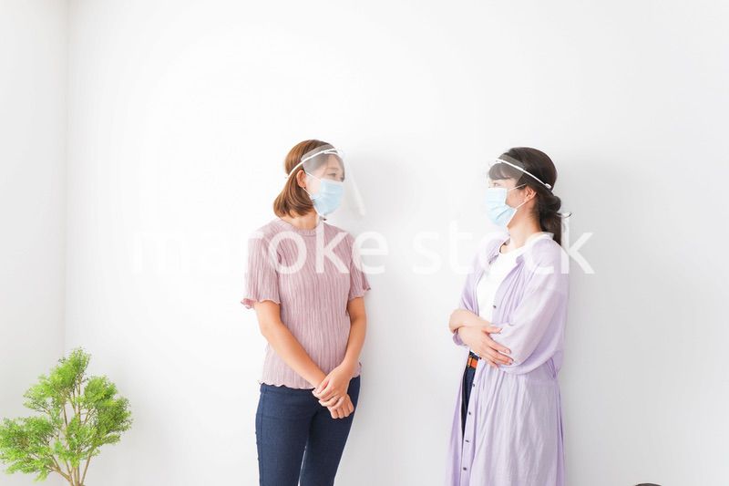 フェイスシールドをして話す若い女性