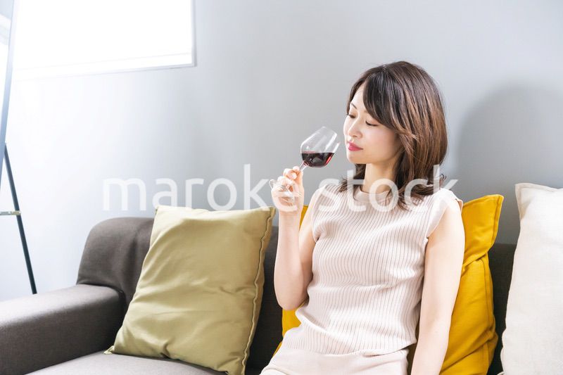 家でワインを楽しむ若い女性