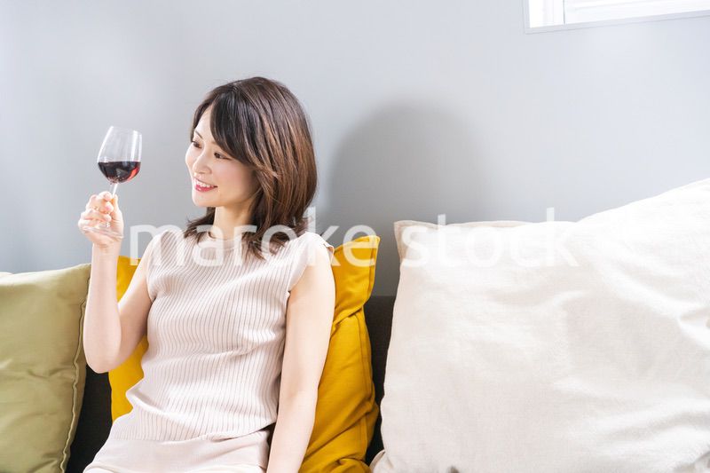 家でワインを楽しむ若い女性