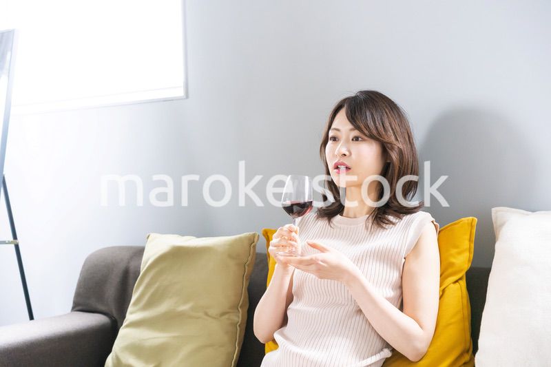 家でワインを楽しむ若い女性