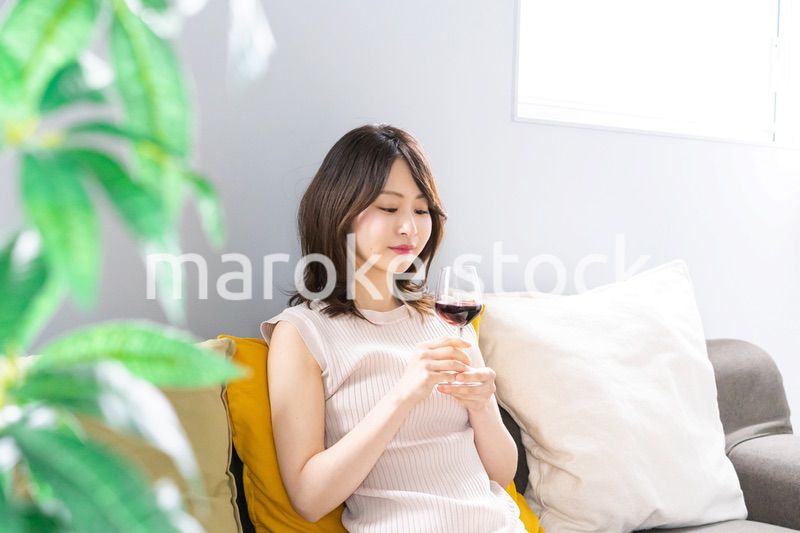 家でワインを楽しむ若い女性