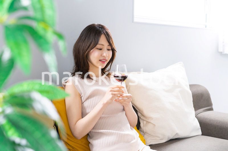 家でワインを楽しむ若い女性