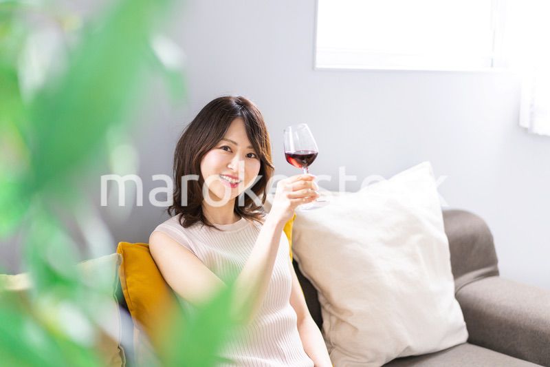 家でワインを楽しむ若い女性