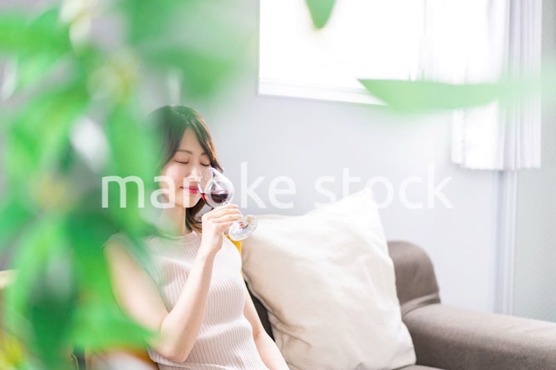 家でワインを楽しむ若い女性