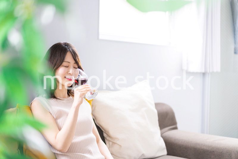 家でワインを楽しむ若い女性