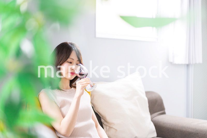 家でワインを楽しむ若い女性
