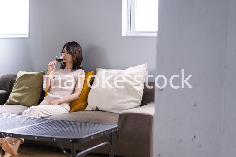 家でワインを楽しむ若い女性