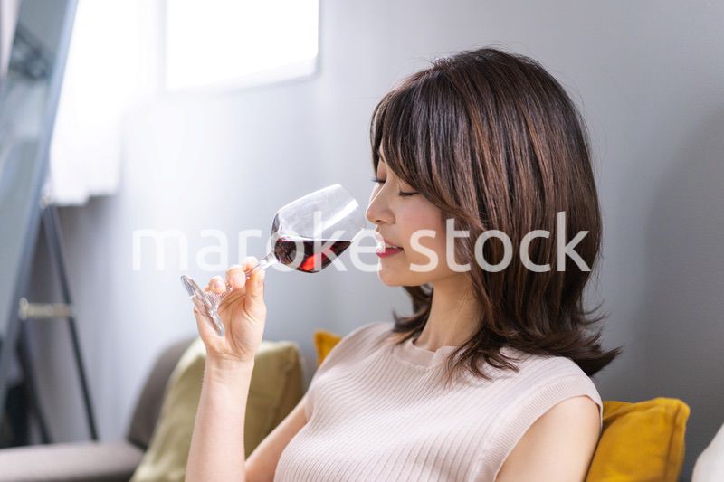 家でワインを楽しむ若い女性