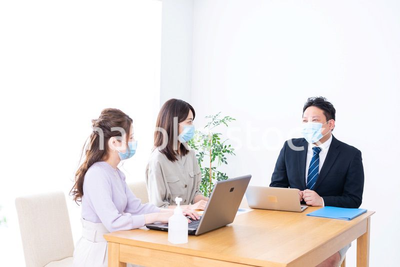 マスクをしてオフィスでデスクワークをするオフィスワーカー